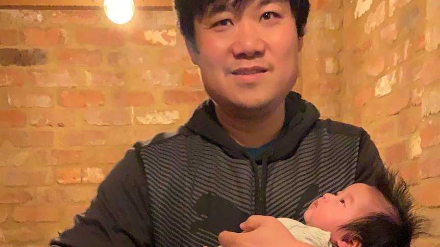 Yi Xu holds his baby daughter, who has been caught in China's coronavirus lockdown.