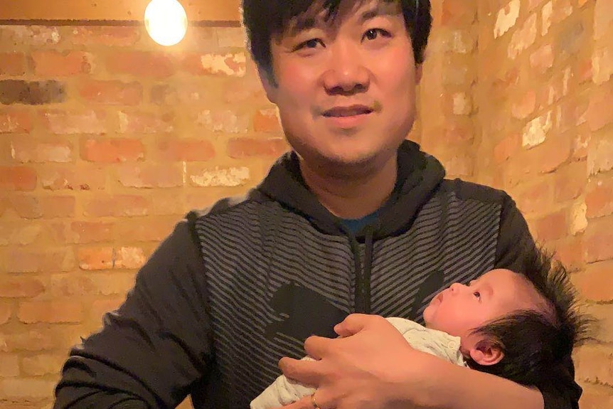 Yi Xu holds his baby daughter, who has been caught in China's coronavirus lockdown.