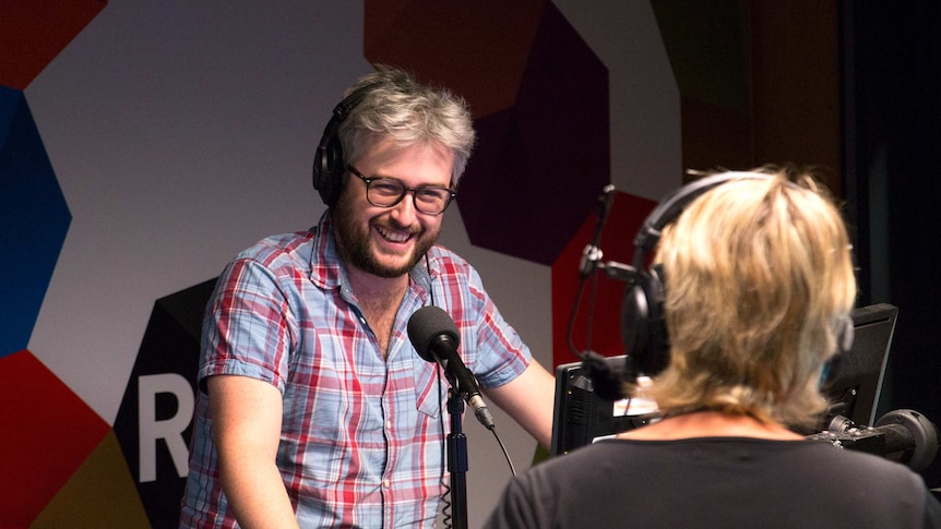 Matt Bevan behind microphone while on air in studio with Fran Kelly.