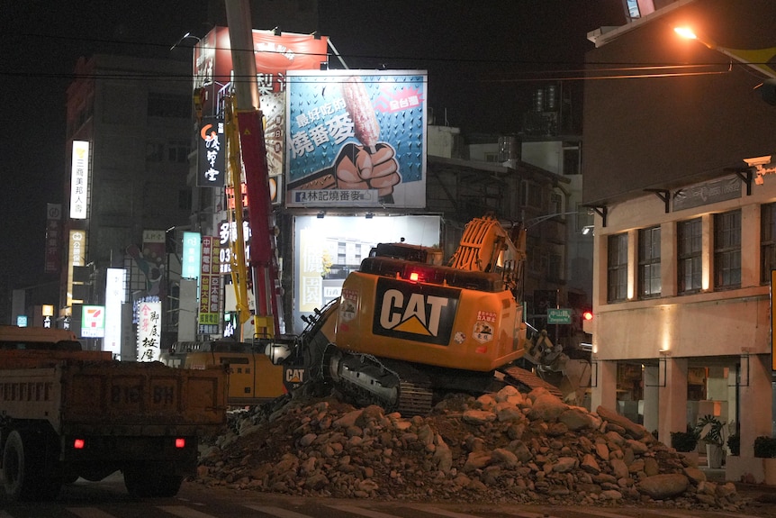 Workers carry out operations near the site where a building collapsed.