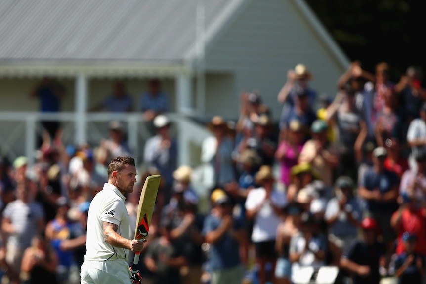 Brendon McCullum raises his bat after making the fastest 100