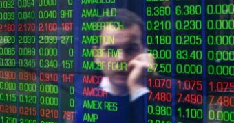 An office worker talks on his phone as he looks the stock board at the Australian Securities Exchange