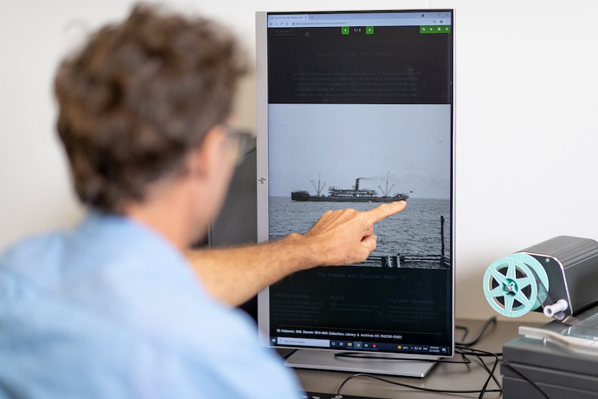 Dr Charlie Ward looks at and points to a digital image of a ship on a screen .