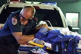 A paramedic attends to a partygoer on a stretcher with an oxygen mask.