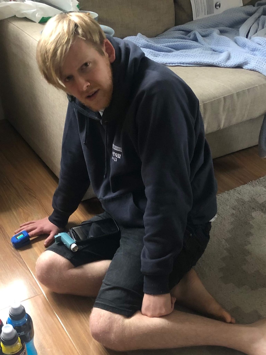Sam Martin on his knees on the floor in his home as he struggles to stand while infected with COVID19.