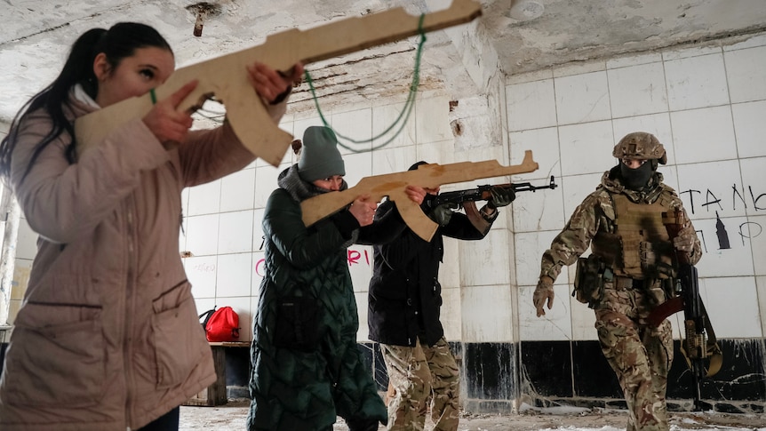 Three women holding fake model guns stand in a room