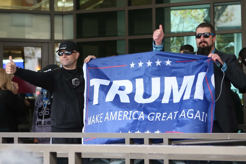 Members of the United Patriots unfold a Donald Trump  banner outside the Melbourne Magistrate court.