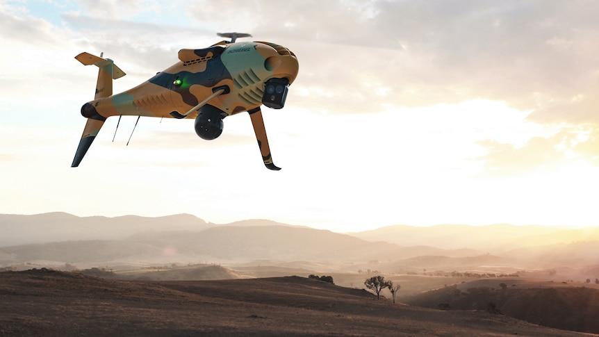 A yellow helicopter drone flying in the sky.