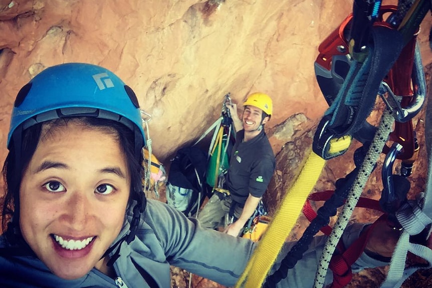 Two rock climbers taking a selfie together on a rock face.