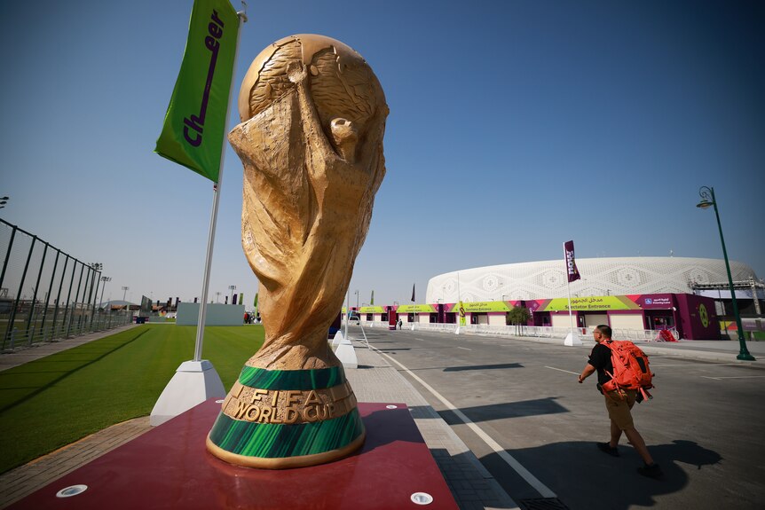 A giant World Cup trophy is set up down the street from a football stadium in Doha