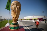 A giant World Cup trophy is set up down the street from a football stadium in Doha