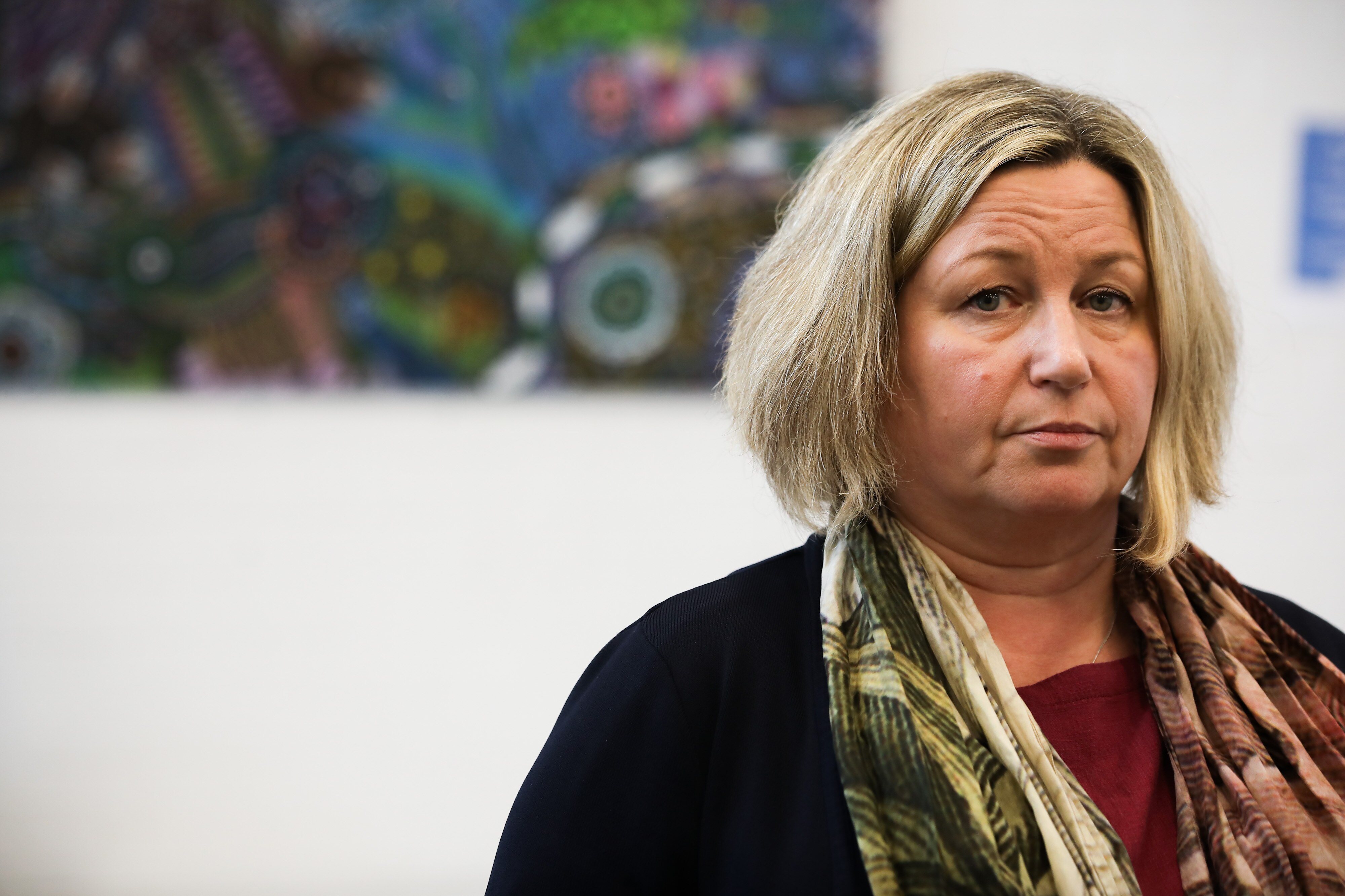 A woman with blonde hair wears glasses and smiles for the camera. 