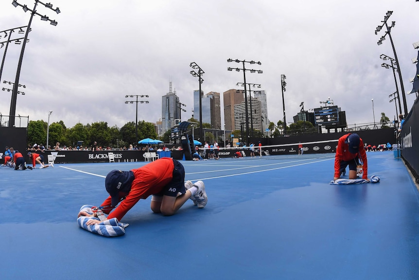 Ballboys dry outdoor court after rain at the Australian Open