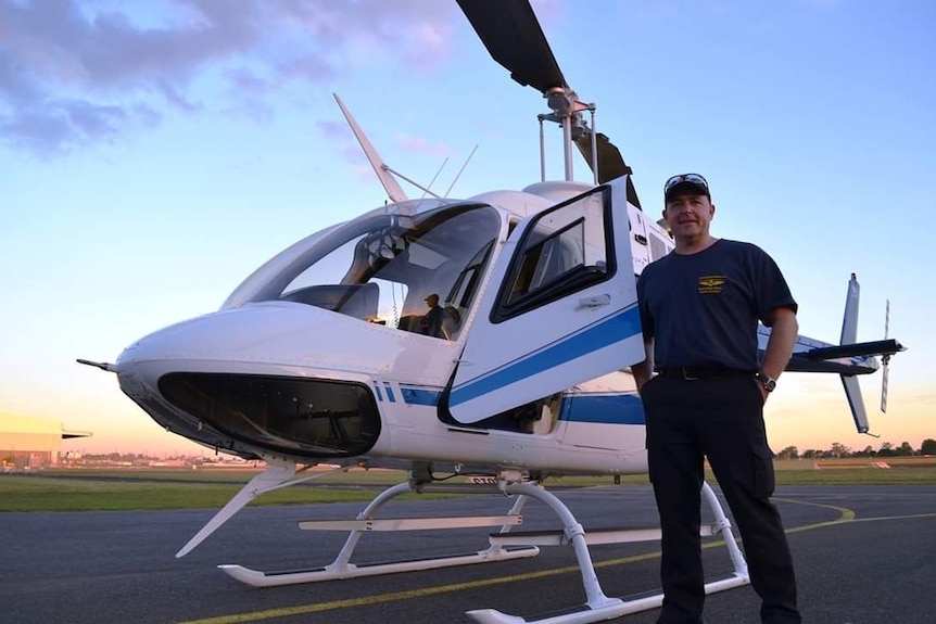 A man standing in front of a helicopter