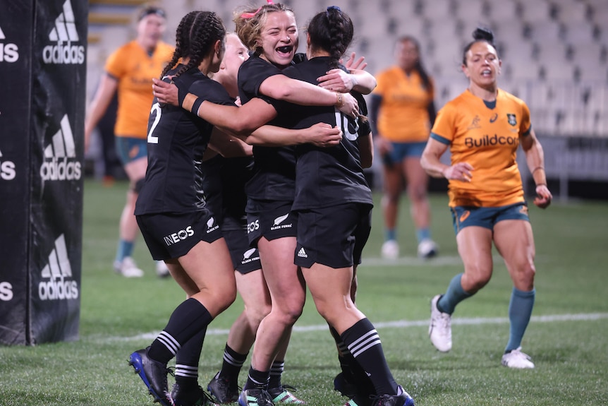 Black Ferns players embrace after scoring a try against the Wallaroos.