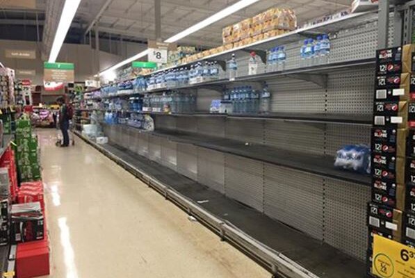 Almost bare supermarket shelves in Port Hedland with a few bottles of water remaining.