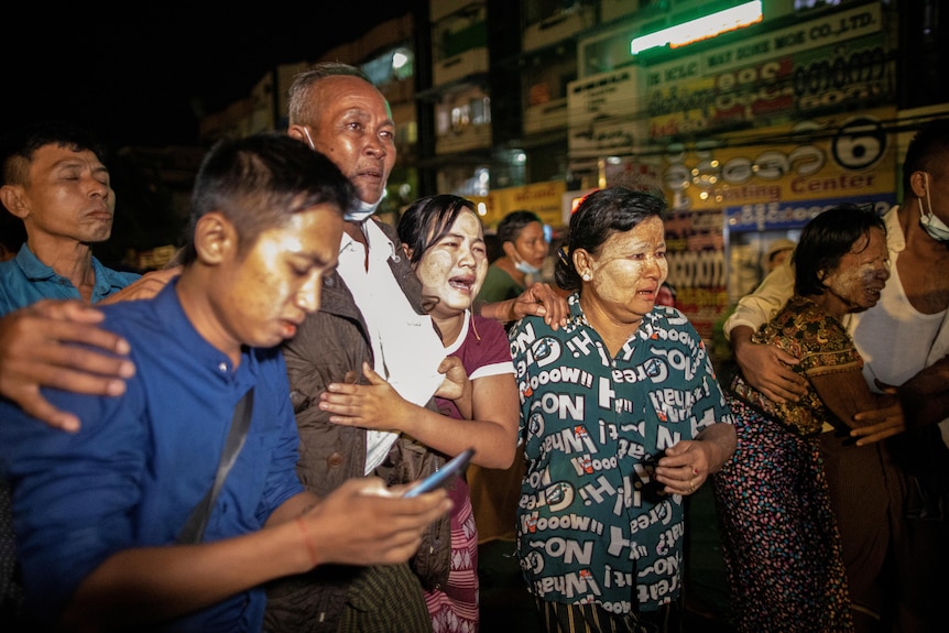 A group of men and women wait expectantly. 