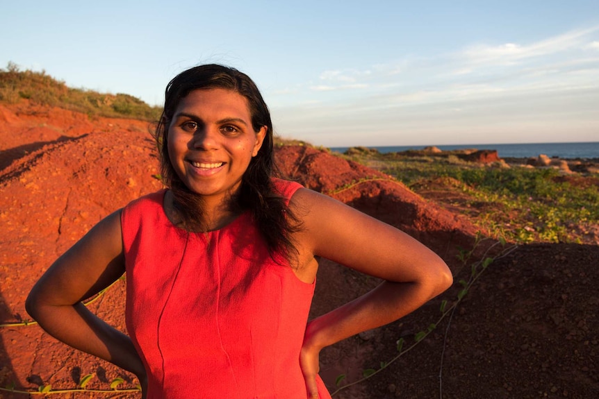 Molly stands against a red earth headland illustrating her guide to finding love in the Kimberley region of Western Australia.