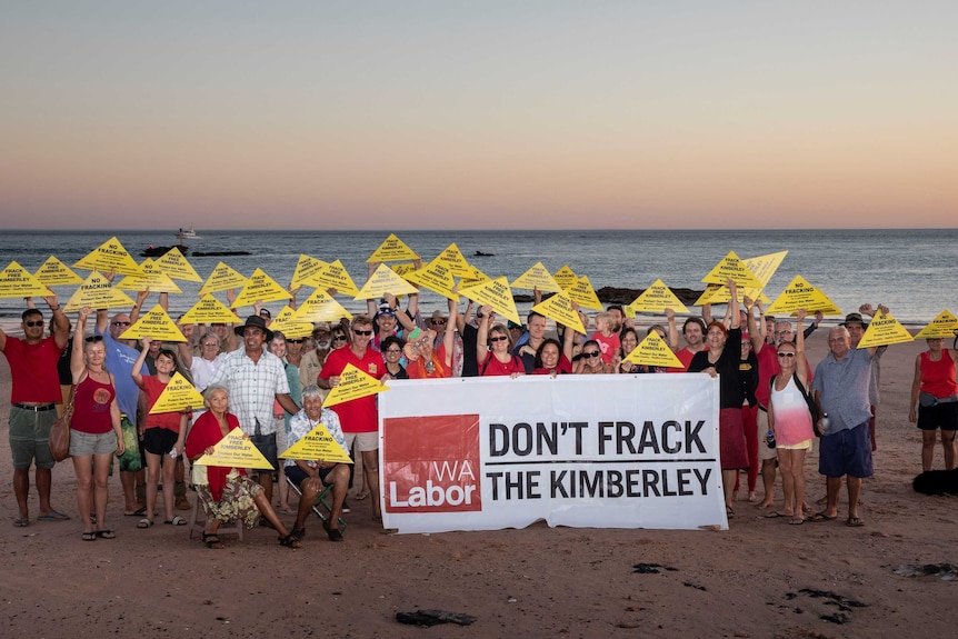 Protestors hold signs opposing fracking.