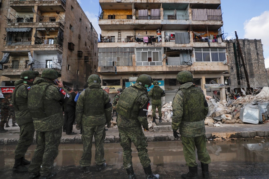 Russian soldiers and security forces check the wreckage of collapsed buildings in Aleppo.