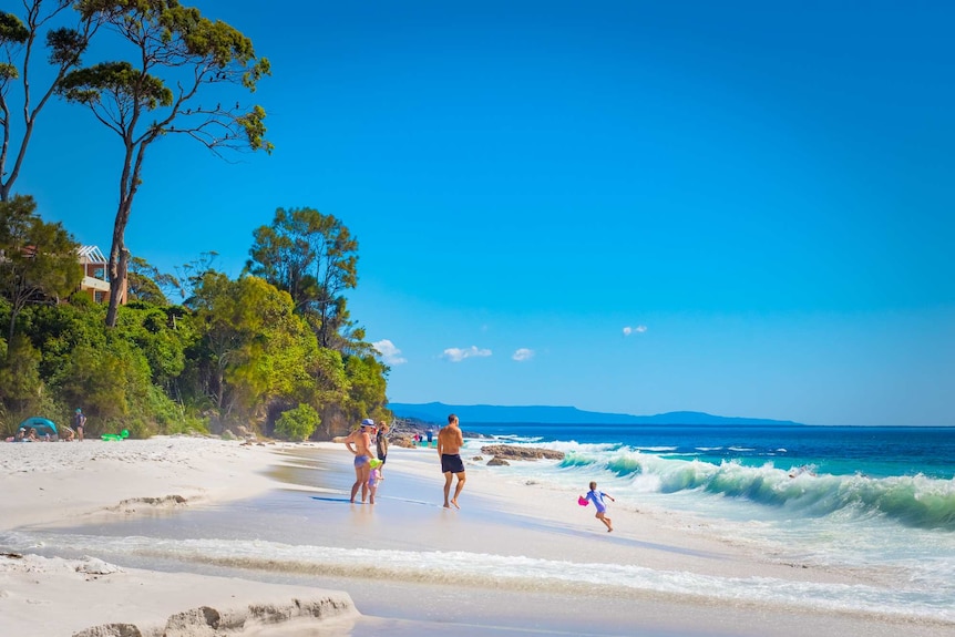 A family plays on the sand next to a picturesque beach