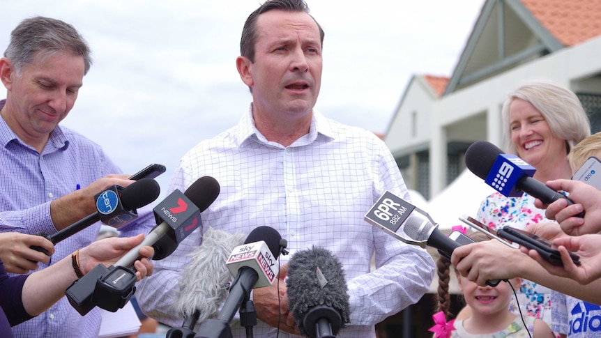 A mid-shot of Mark McGowan speaking to reporters with microphones in front of him.