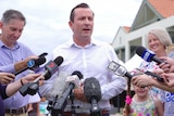 A mid-shot of Mark McGowan speaking to reporters with microphones in front of him.