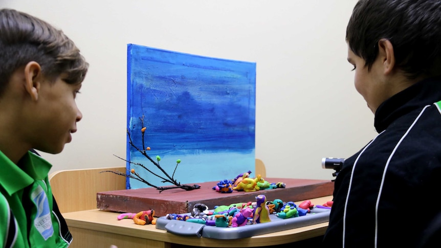 Two school students look at their plasticine models.