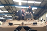 Tasmanian Premier Will Hodgman (l) inspects the prototype defence vehicle built in Burnie, with Braddon MP Brett Whiteley and business owner Dale Elphinstone (r)