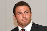 Sam Burgess sitting in a suit at an NRL judiciary hearing in 2017.