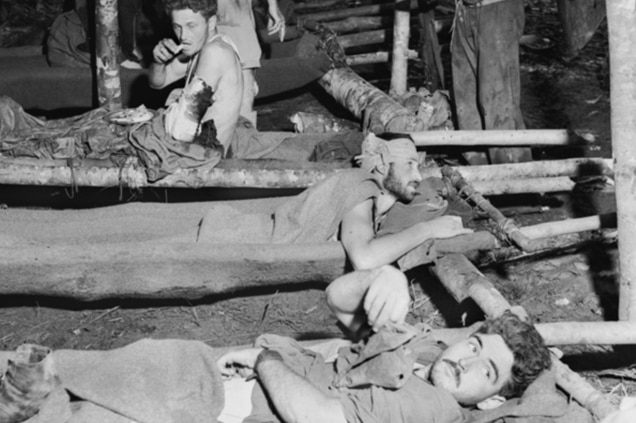 Wounded soldiers from the Battle for Gorari in Papua New Guinea in WWII lay on makeshift stretchers in November 1942.