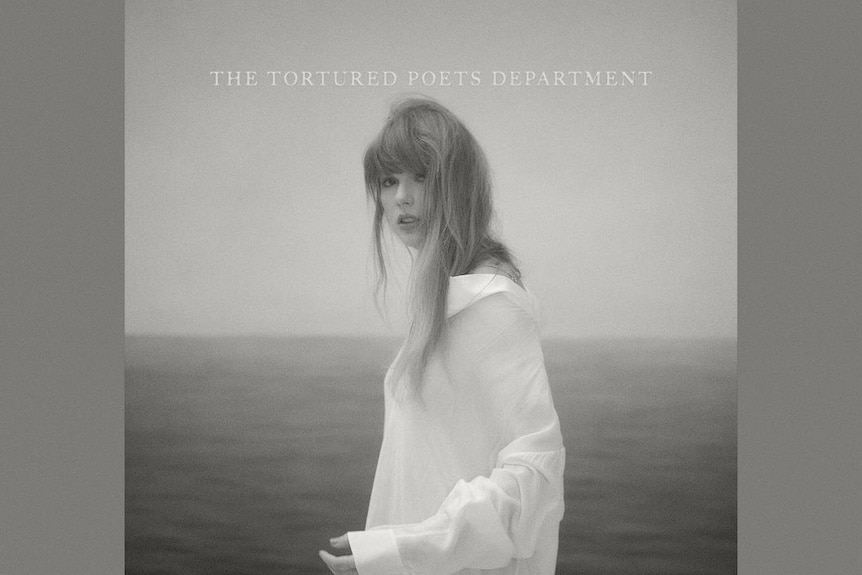 Taylor Swift's new album cover in black and white with Taylor standing in the middle in a long white t shirt
