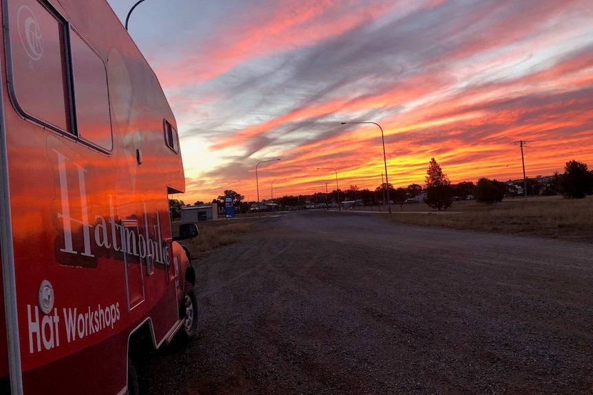 A red van sitting on the side of the road before sunset