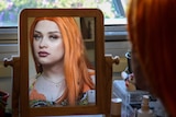 Transgender teenager Aliza looks at her finished make-up in the reflection of a mirror