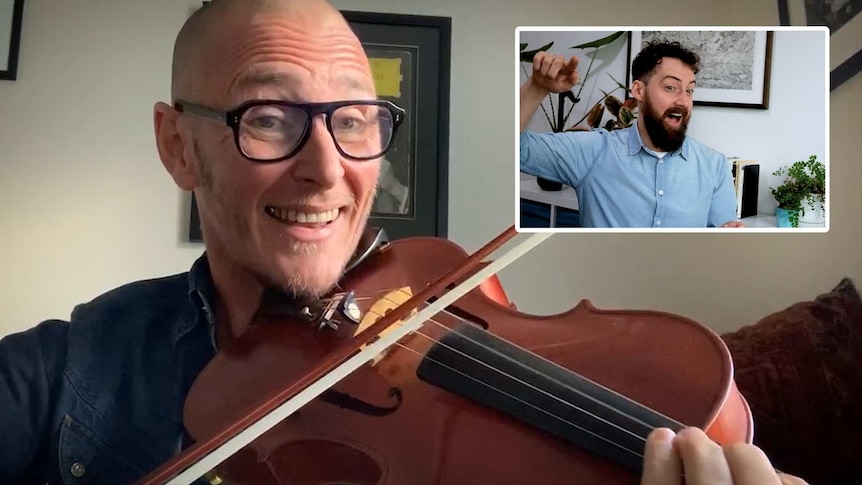 A man in glasses plays the viola with a smile on his face