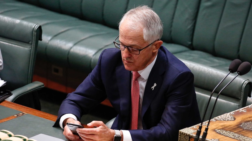 Prime Minister Malcolm Turnbull uses his phone in the House of Representatives