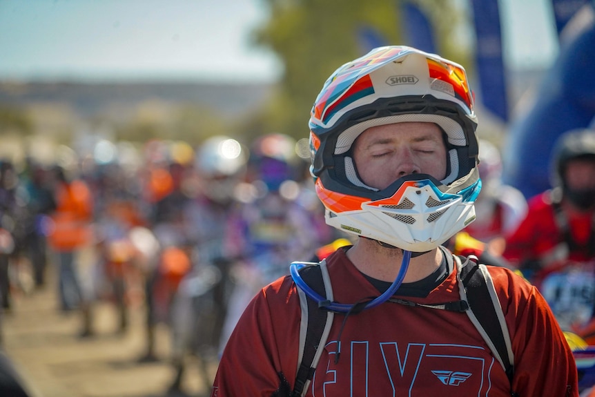 man in bike helmet sitting at start line of race, eyes closed