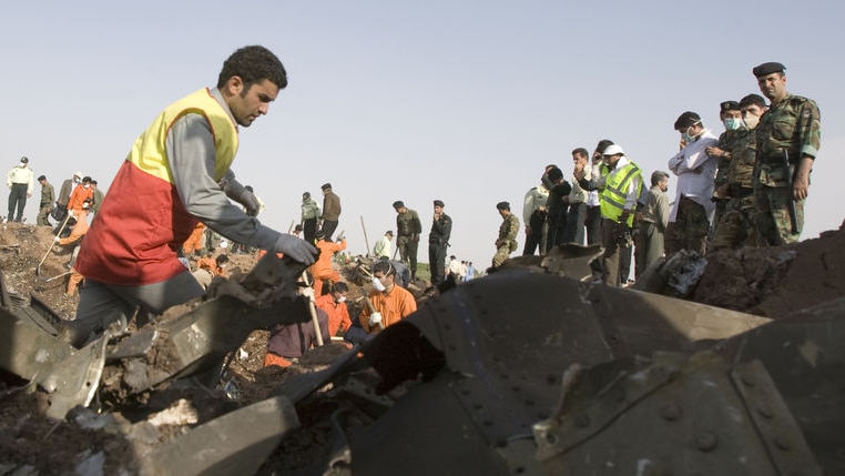 A volunteer looks through wreckage from a plane crash in Iran
