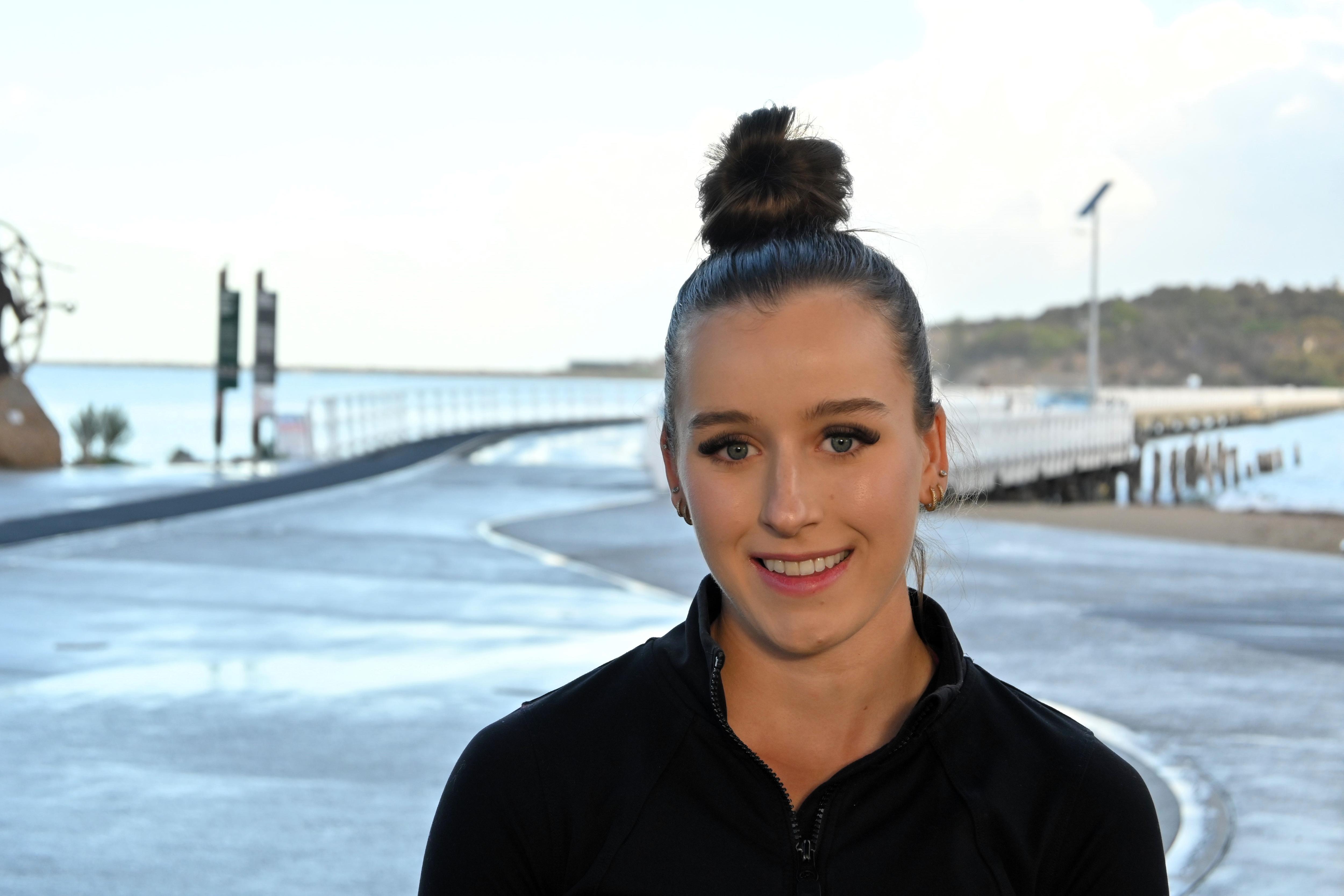 A young woman stands on a path leading to a bridge