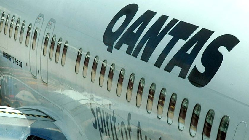 A domestic Qantas jet sits at a gate