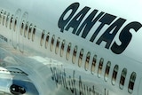 A domestic Qantas jet sits at a gate