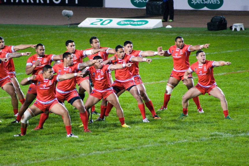 Rugby players wearing red uniforms perform the Sipi Tau war dance.