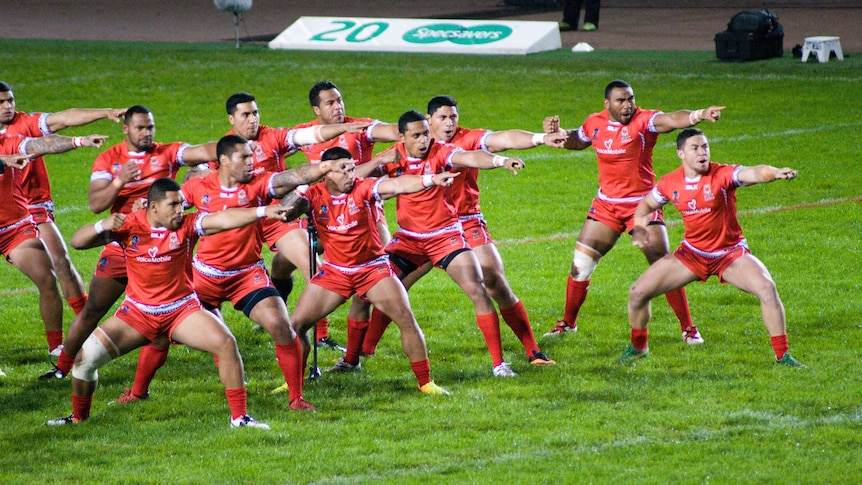Rugby players wearing red uniforms perform the Sipi Tau war dance.