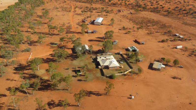 an aerial photo of a house and sheds on red dirt.