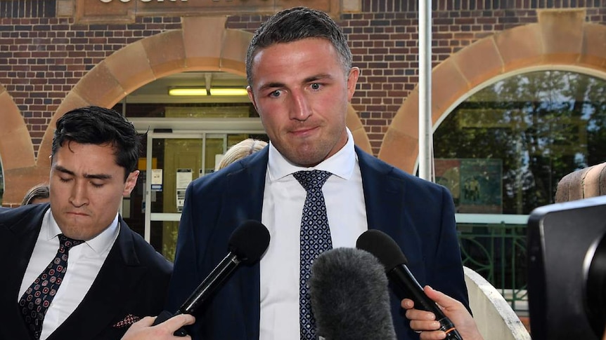 A man leaves court with reporters in front of him