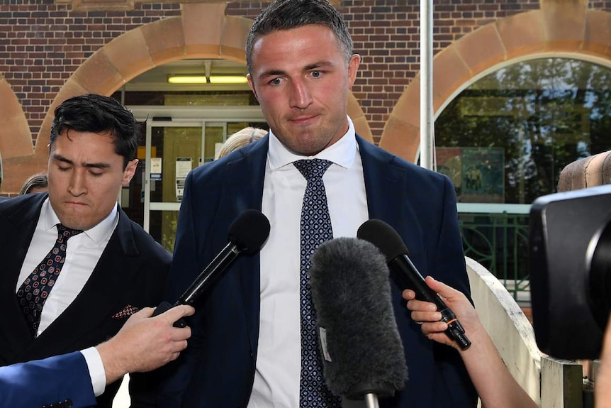 A man leaves court with reporters in front of him