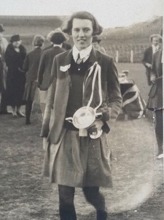 Black and white photo of a girl in school uniform holding a trophy.