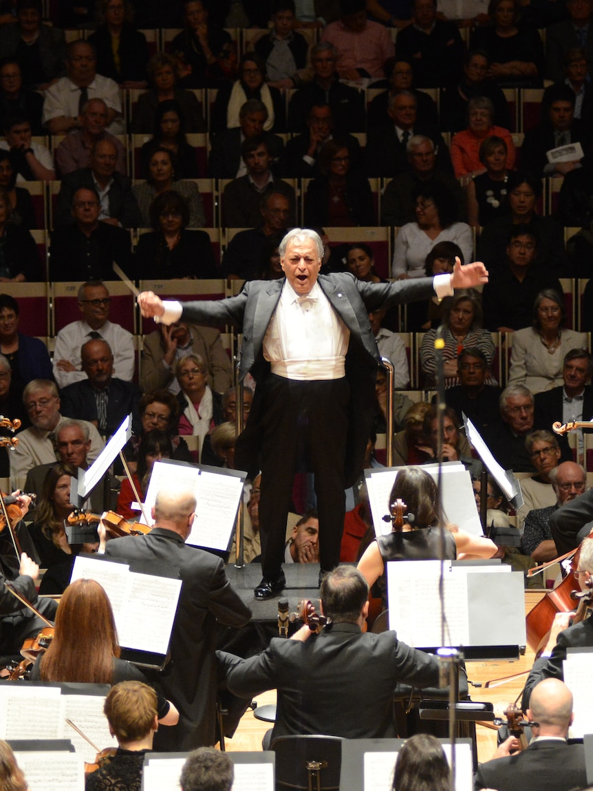 Maestro Zubin Mehta with arms outstretched as he conducts the Australian World Orchestra. 