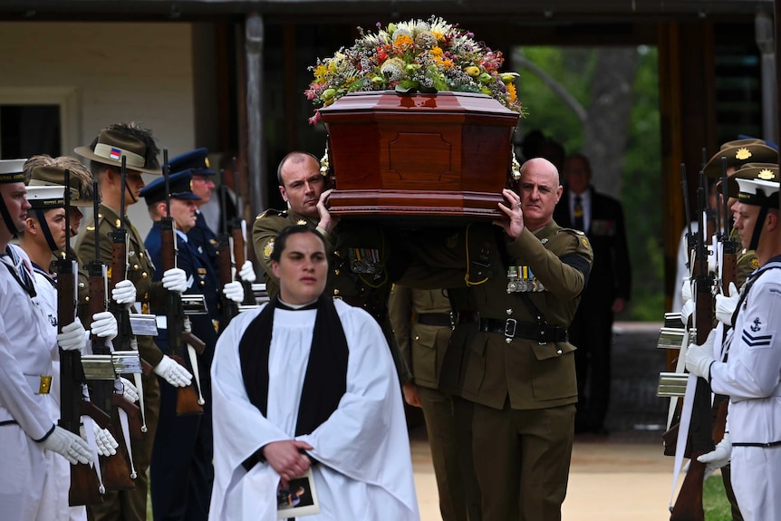 A military guard stands by as a coffin is carried from the chapel.