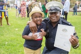 A young African boy with an African man in police uniform holding a citizenship paper